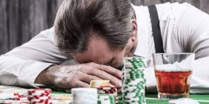 Man in distress surrounded by gambling paraphernalia, illustrating the dark side of financial infidelity tied to gambling debts.