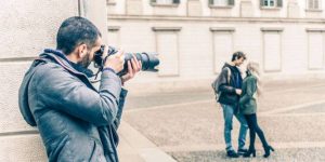 Private investigator, holding a magnifying glass and photograph, looking intently for clues. Text overlay: "How much does a private investigator cost?"