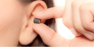 A close-up view of a spy listening device being discreetly inserted into an ear.