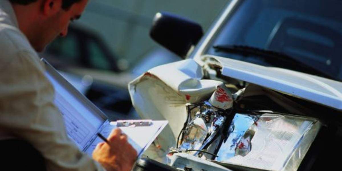 Insurance investigator examining a car crash for signs of car insurance fraud.
