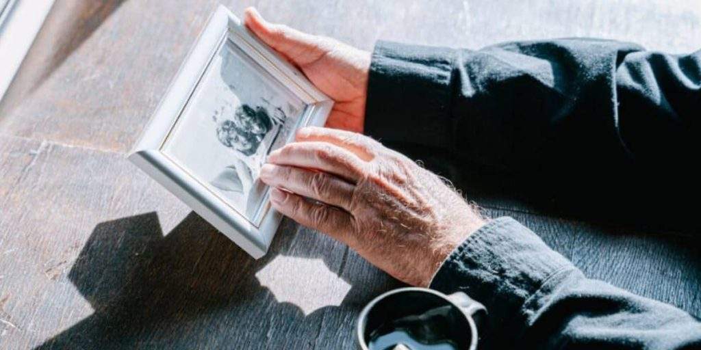 A family member tenderly caressing a photo of a missing loved one, illustrating the emotional journey to locate a person