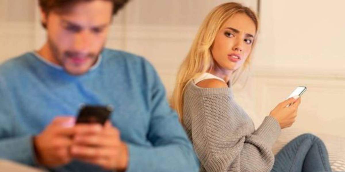 "Wife looking suspiciously at husband discreetly texting, hinting at marriage infidelity."