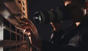 A private investigator charges forward, holding a camera